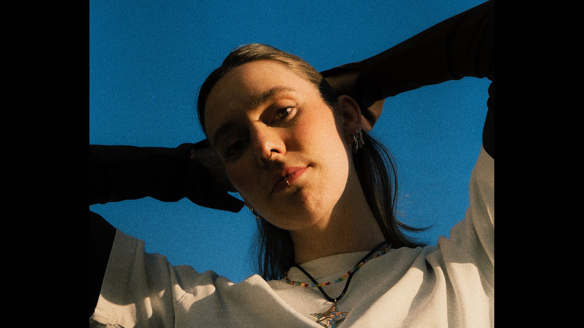 EIn Foto der Künstlerin Malou Lovis mit den Armen über dem Kopf