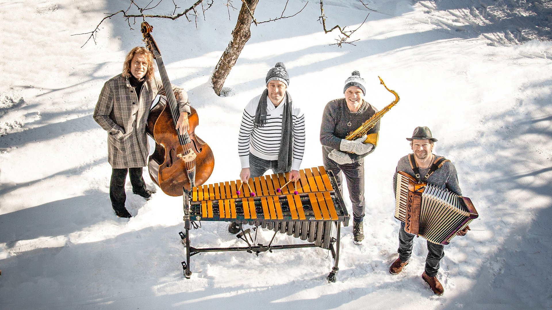 Die vier Musiker der Band Quadro Nuevo mit Instrumenten ein einer Winterlandschaft