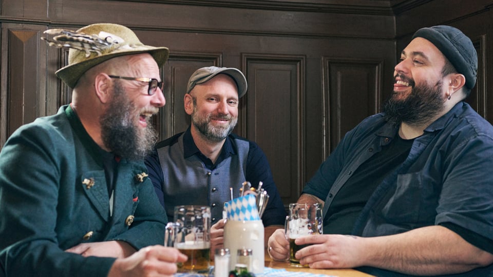 Drei Herren mit Bierkrügen an einem Tisch