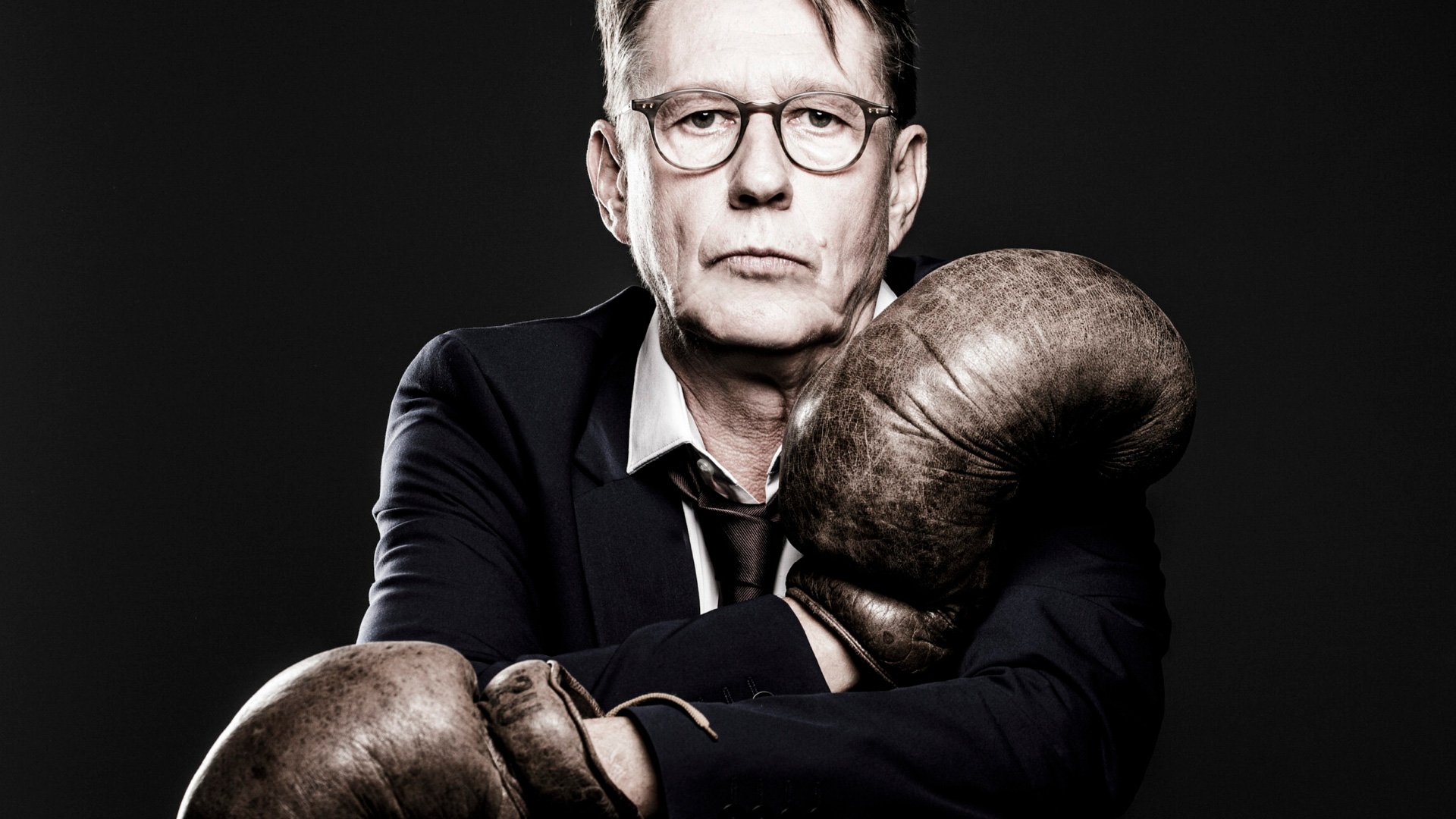 Foto für die Veranstaltung Andreas Rebers mit dem Künstler, der Boxhandschuhe trägt, vor schwarzem Hintergrund