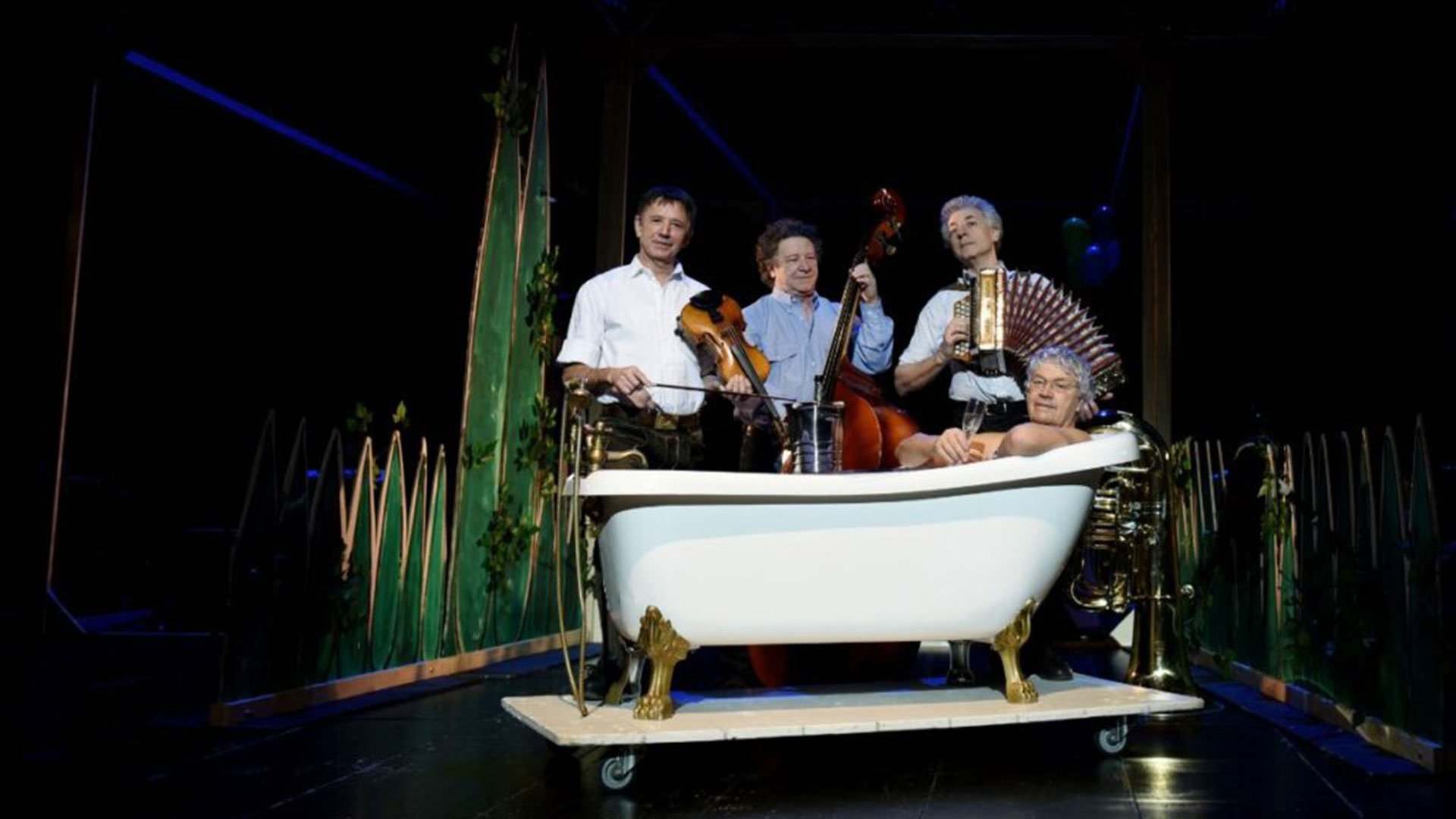 Veranstaltungsfoto von ‚Well Brüder & Wellküren – Familienbande‘ mit Ensemble auf der Bühne und einem Darsteller in einer Badewanne.