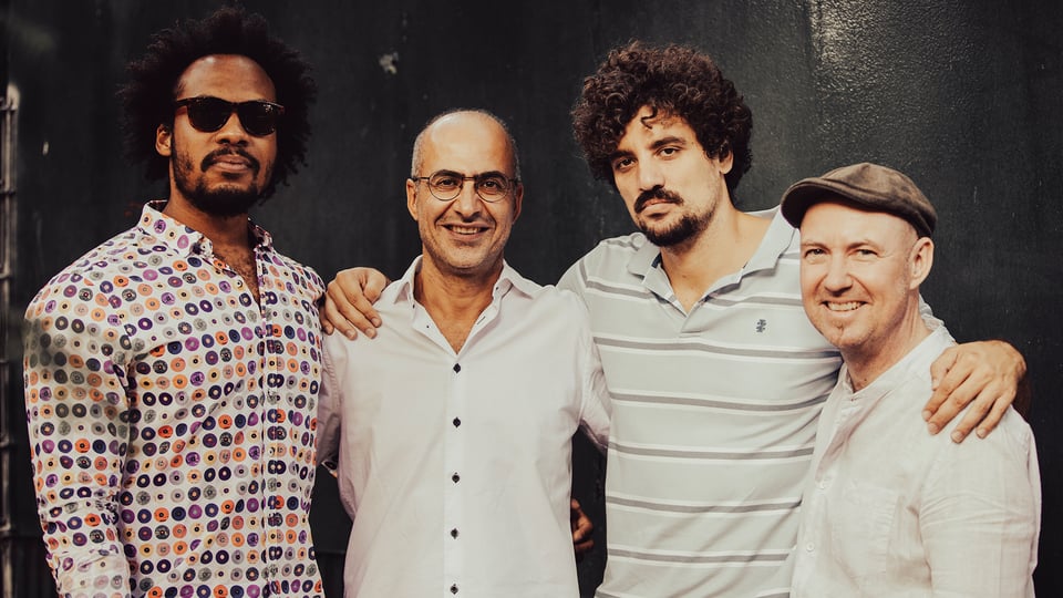 Ein Foto der vierköpfigen Band vor dunklem Hintergrund