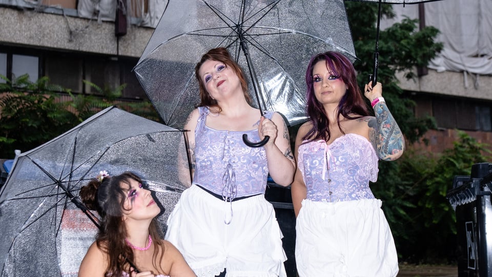 Drei Damen mit langen Haaren und Regenschirmen