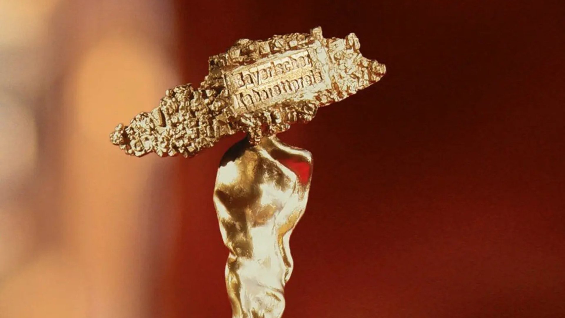 Copilot said:  Detailaufnahme der Trophäe des Bayerischen Kabarettpreises mit goldfarbener stilisierter Figur und Plakette mit der Aufschrift Kabarett Memorandum vor unscharfem rotbraunem Hintergrund