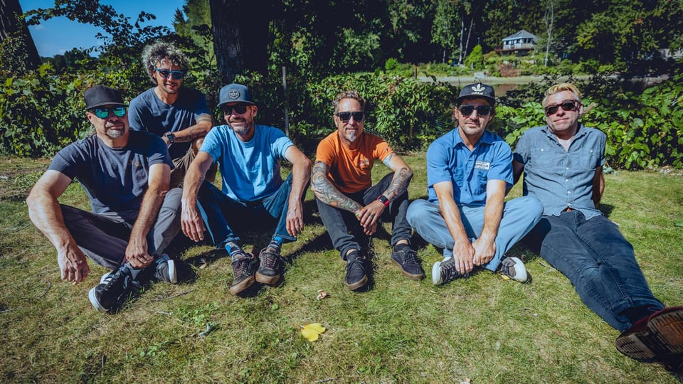 Die Bandmitglieder auf einer Wiese sitzend