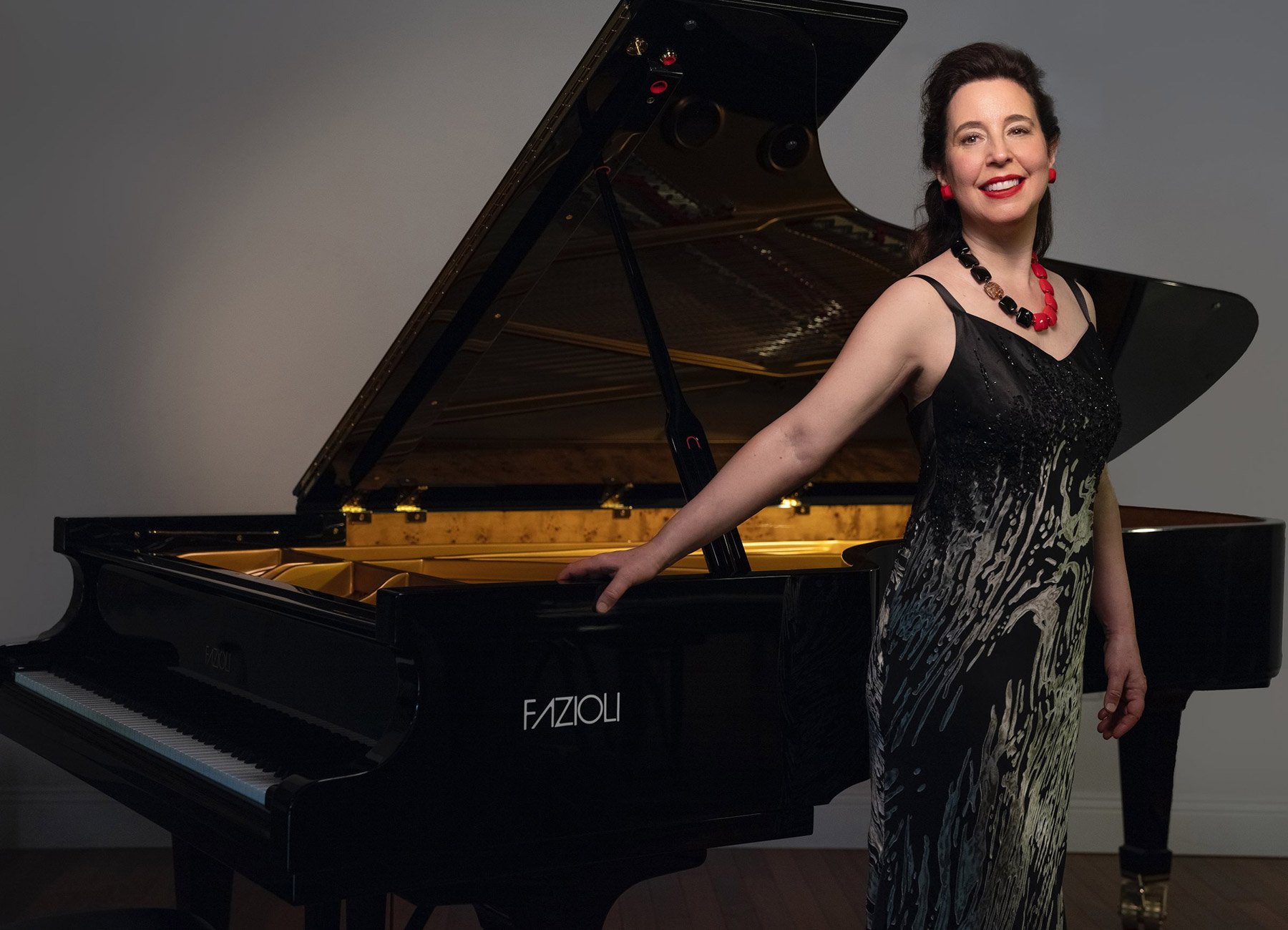 Porträt der Pianistin Angela Hewitt mit einem Flügel im Hintergrund – klassische Musikszene