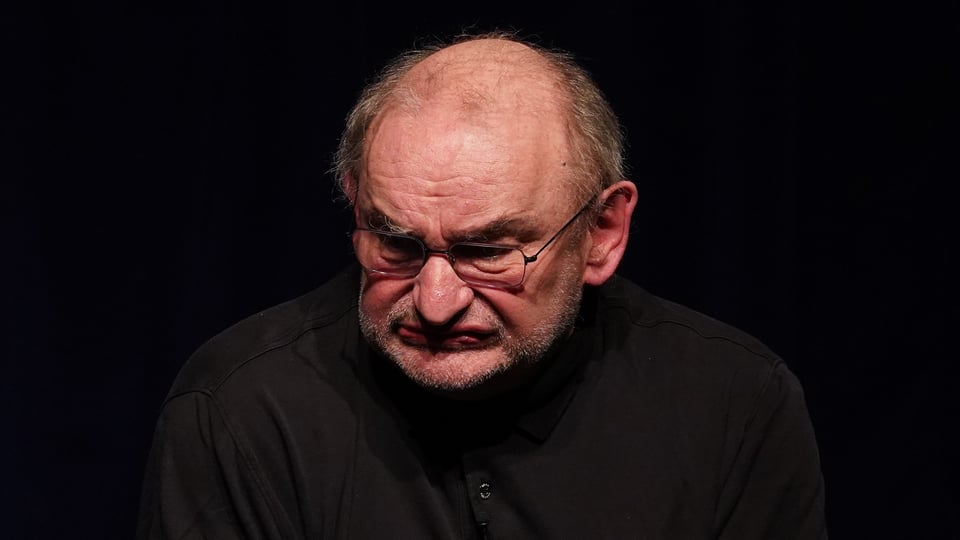 Person sitzt nachdenklich vor schwarzem Hintergrund