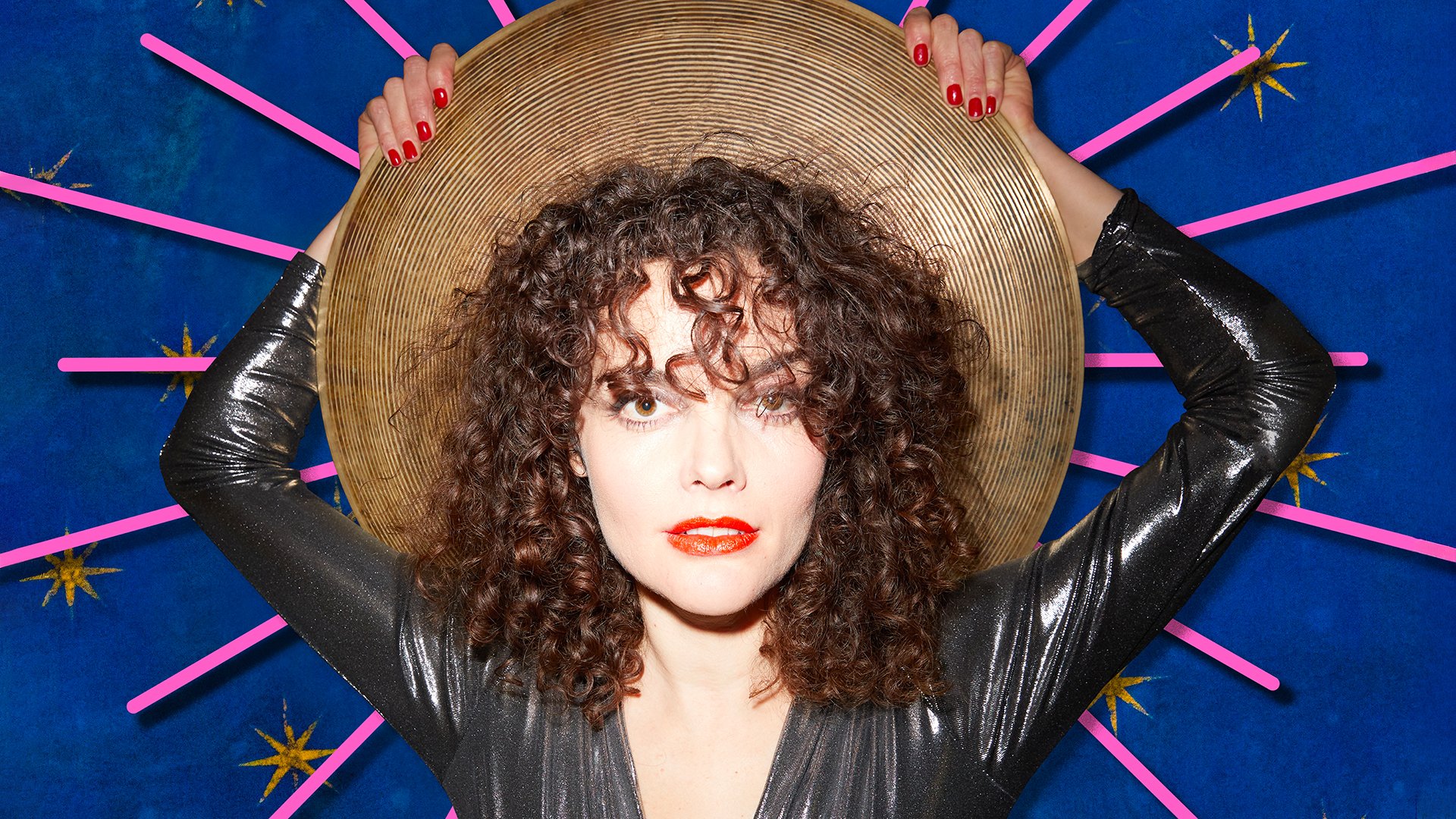 Ein Foto von Maria de Val mit einer Art Hut in den Händen vor blauem-pinker Grafik