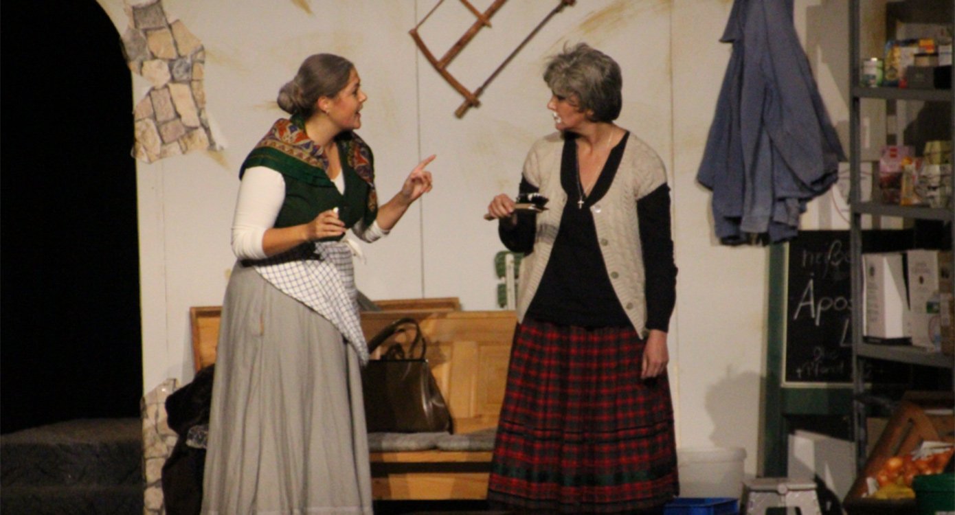 Zwei Damen auf einer Bühne mit rustikalem Hintergrund