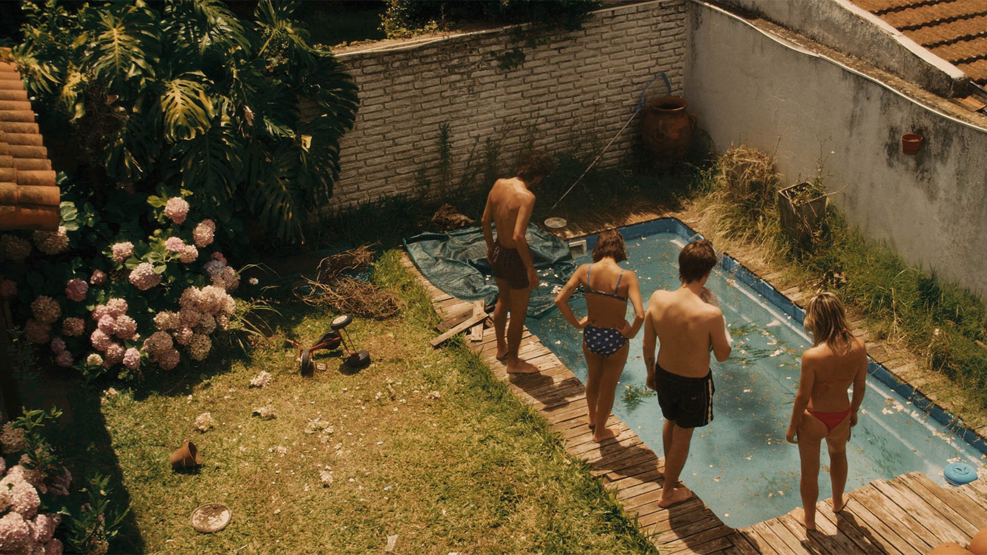 4 Kinder in Badeklamotten befinden sich im Garten vor einem kleinen Pool.