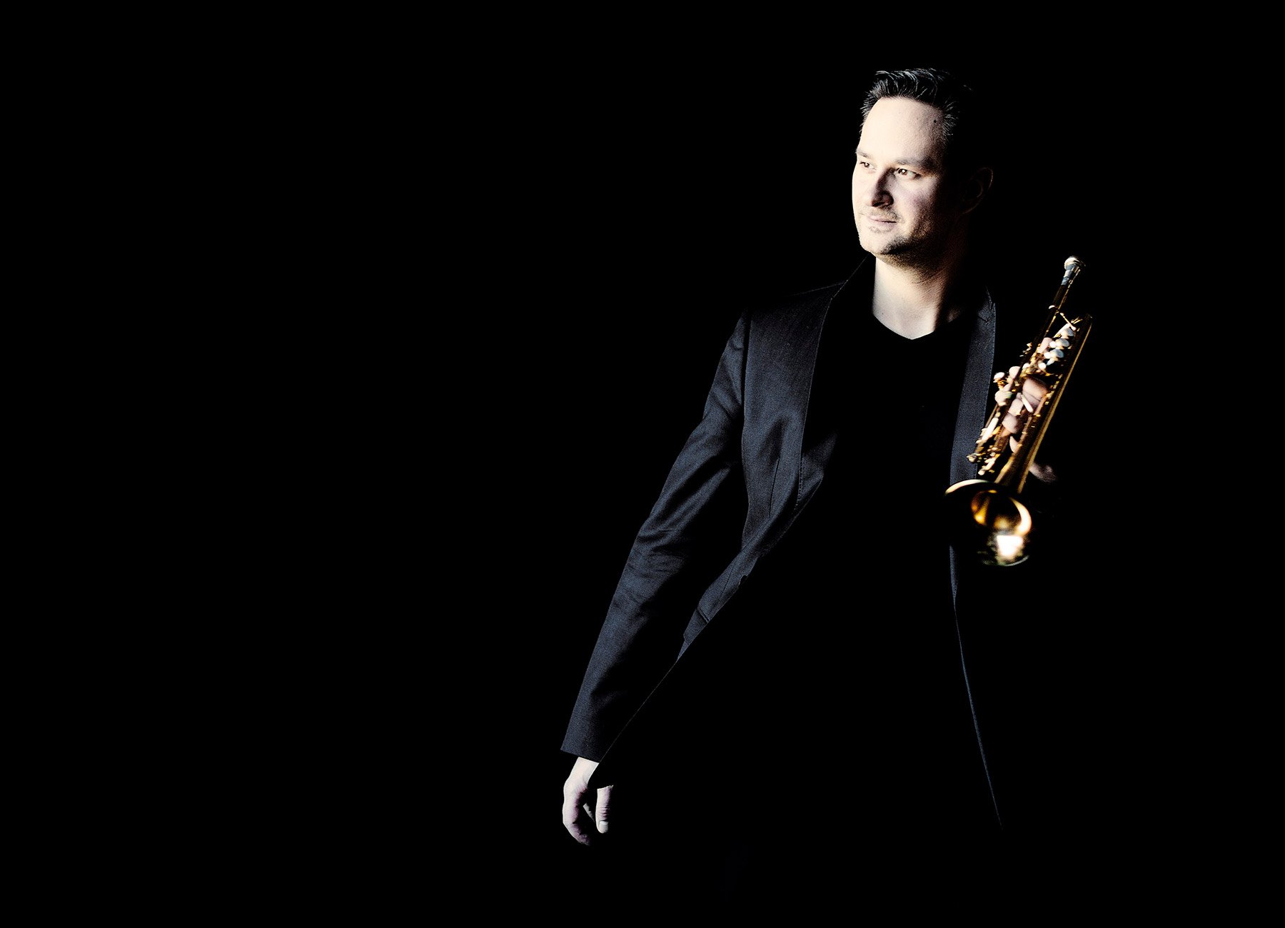 Porträt des Trompeters Gábor Boldoczki mit Instrument in der Hand – vor schwarzem Hintergrund