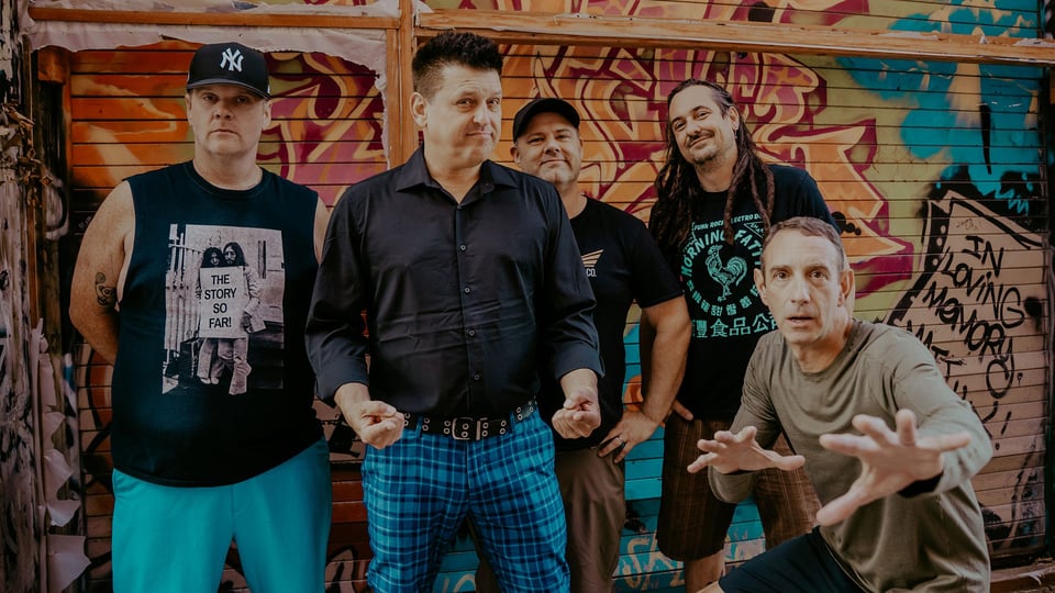 Foto für das Less-Than-Jake-Event mit den Künstlern und einer Graffiti-Wand im Hintergrund.