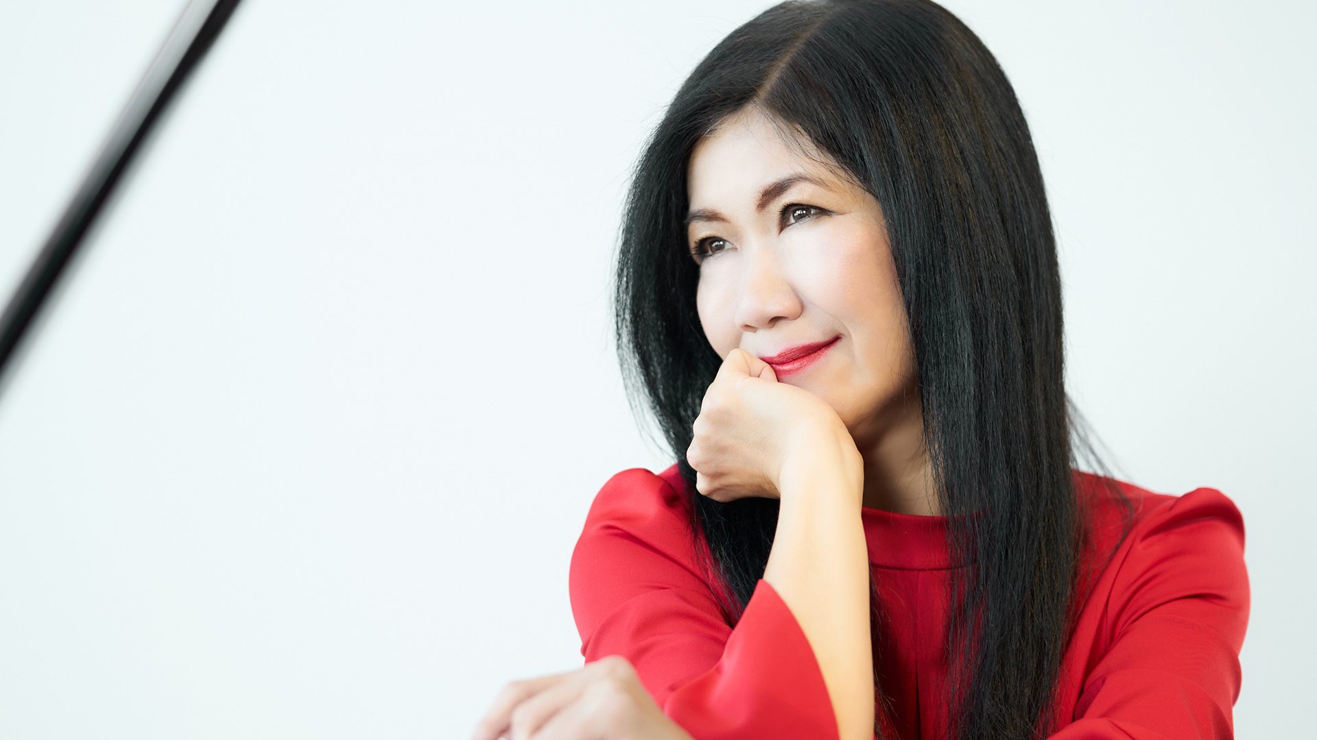 Die Künstlerin in roter Kleidung, das Kinn in die Hand gestützt