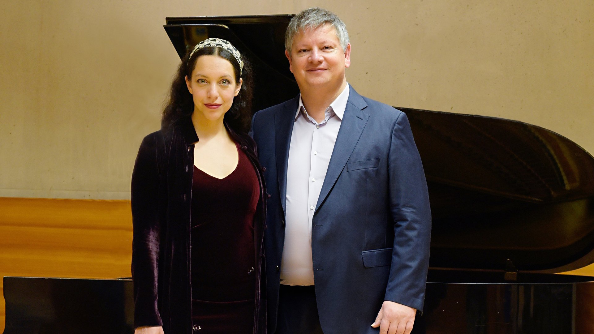 Foto für die Veranstaltung ‚Franz Schubert: Die schöne Müllerin‘ mit den zwei Künstlern, einem Klavier und einer gelben Wand im Hintergrund