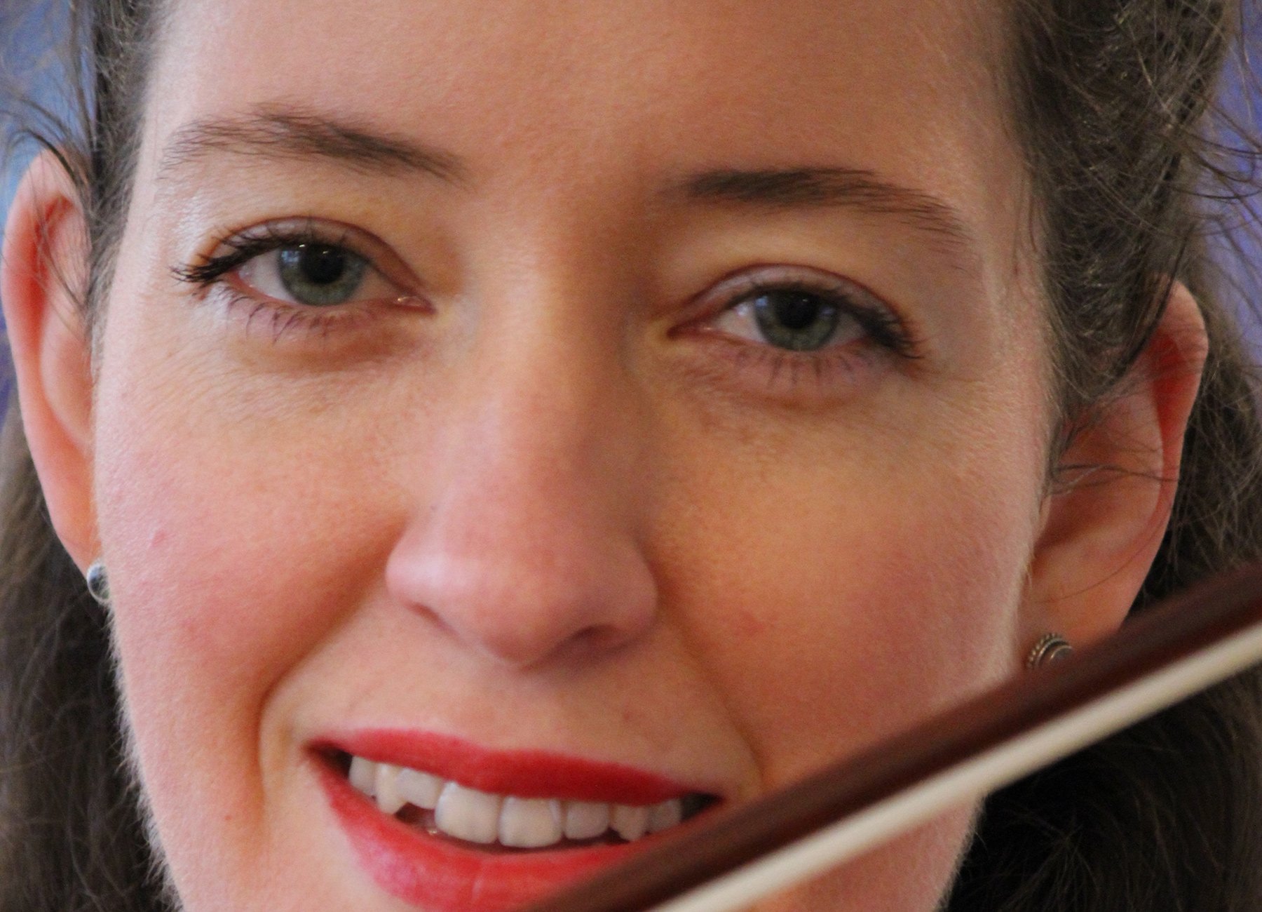 Das Gesicht der Künstlerin Elisabeth Krauss mit rotem Lippenstift und einem Geigenbogen 