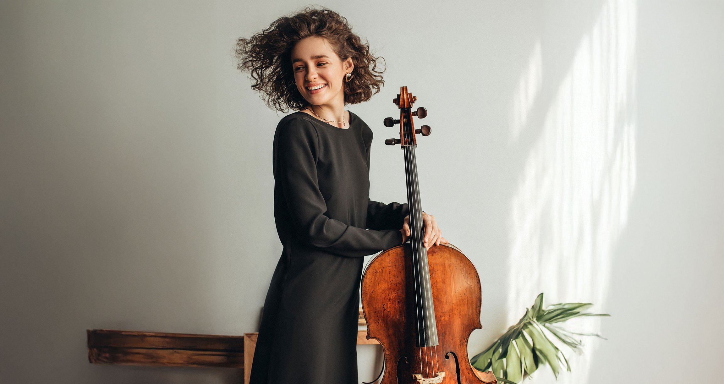 Dame mit Locken on schwarzem Kleid stehend mit Violoncello