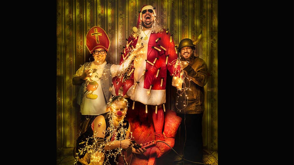 Vier Kabarettisten in weihnachtlichen Kostümen stehen und sitzen vor goldener Tapete mit Lichterketten; zentrale Figur als Nikolaus verkleidet – Werbemotiv zum Weihnachtsprogramm „O‘ghängt is!“ von Da Meier & Watschnbaam.