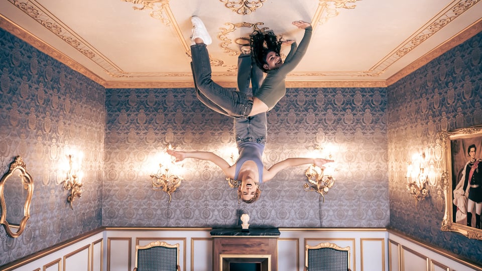 zwei Personen "hängen" mit den Füßen an der Decke eines Schlosszimmers