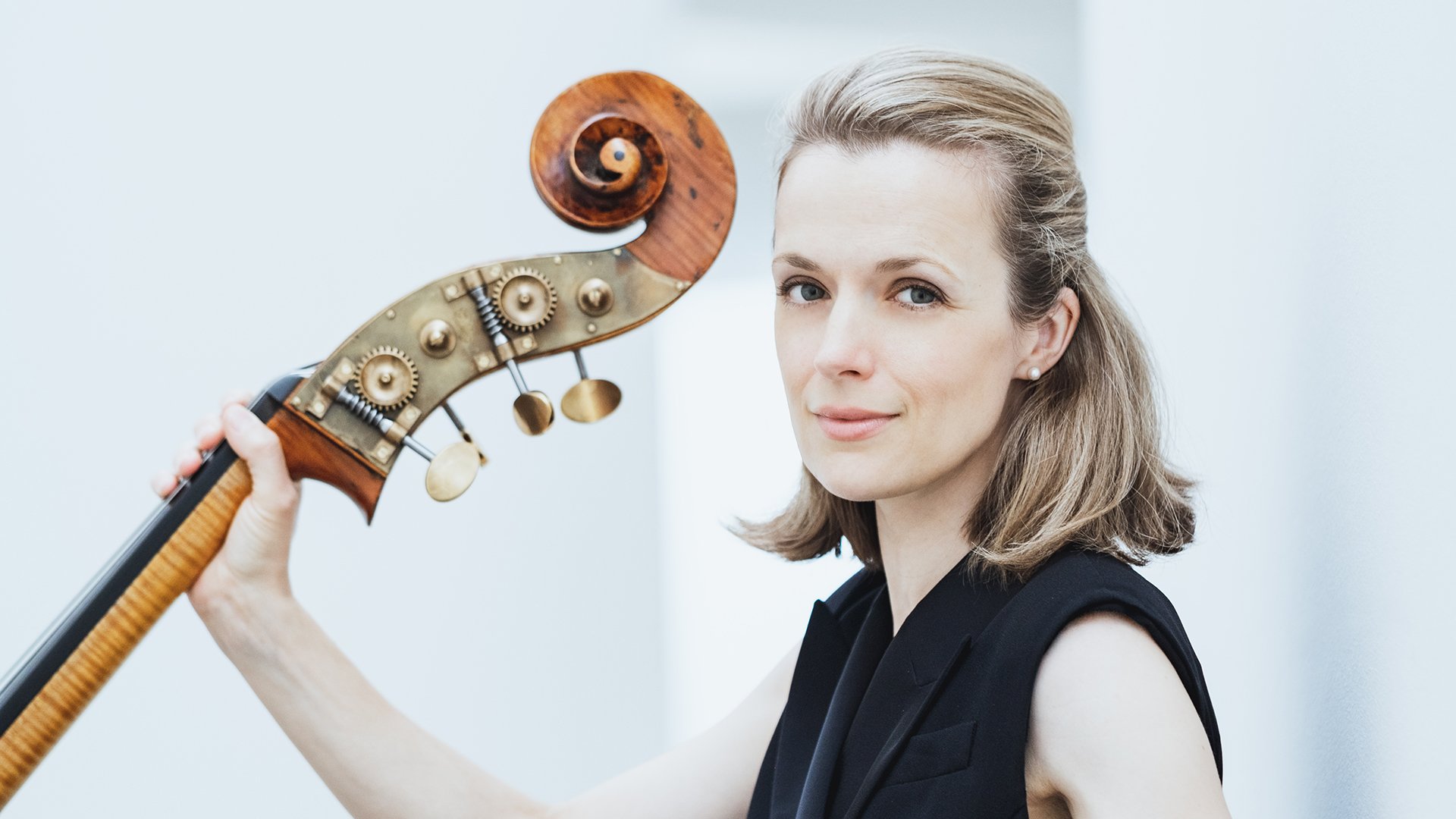 Eine blonde Dame mit Instrument vor hellem Hintergrund