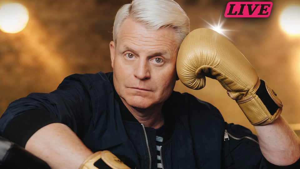 Porträt einer Person mit blondem Haar und goldenen Boxhandschuhen vor unscharfem Hintergrund, mit Schriftzug Live, Pressebild für ein Comedy-Programm.