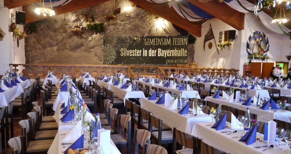 Festsaal mit weiss und blau gedeckten Tischen und Plakat im Hintergrund mit Aufschrift