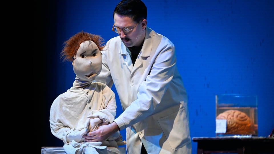 Ein Schauspieler bedient eine Bauchrednerpuppe.