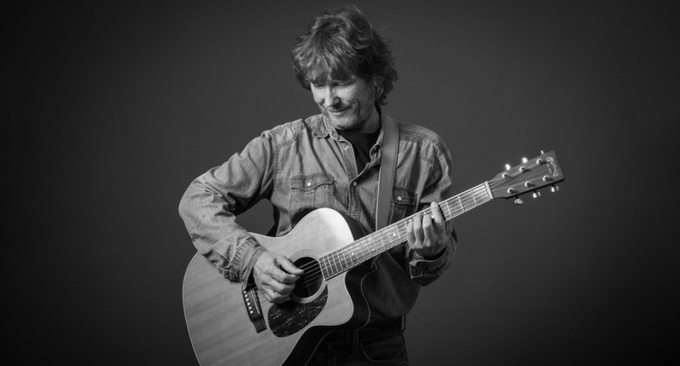 Schwarz-weiss Bild von Mann in Jeanshemd mit Akustikgitarre