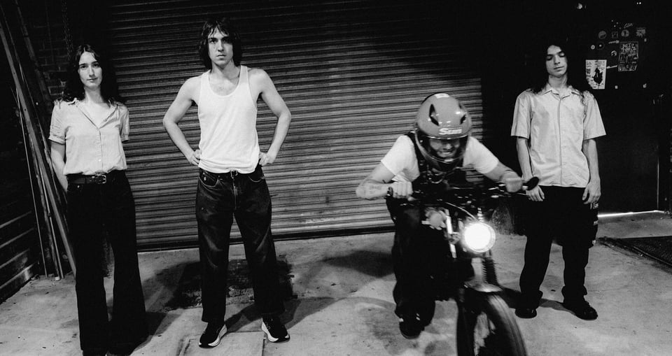 schwarz weiss Bild von vier Personen, eine auf einem Motorrad, vor Garagentor stehend