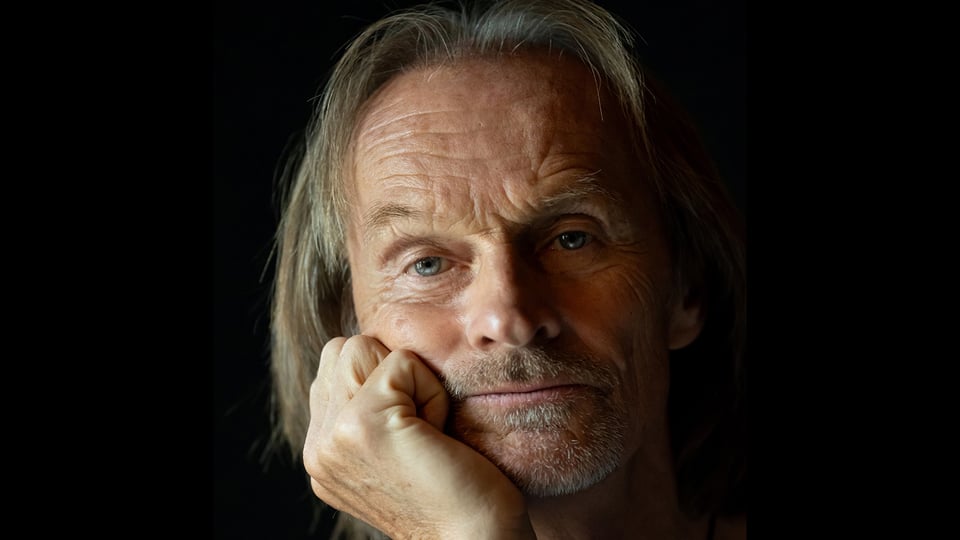 Portrait des Künstlers, der seine Hand auf das Kinn stützt, mit schwarzem Hintergrund