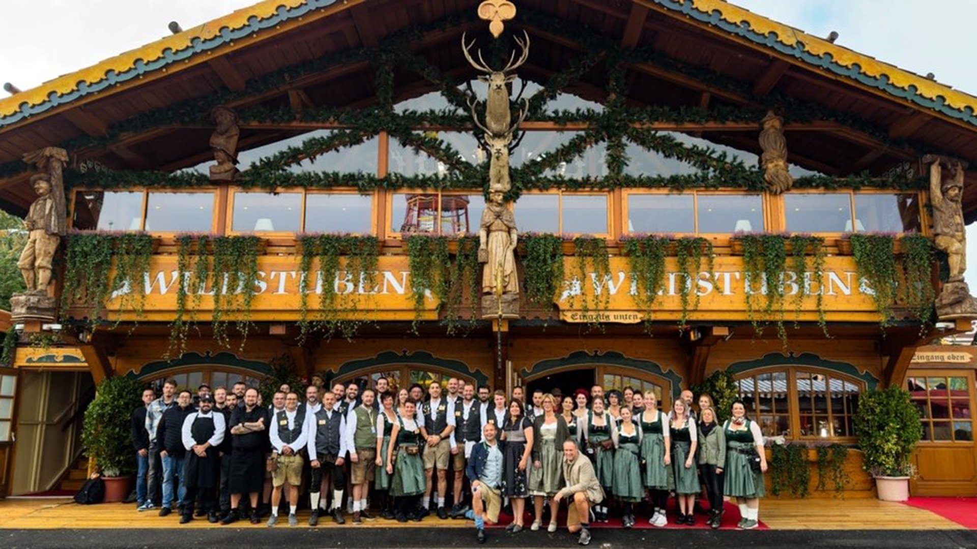 Das Team der Rosa Wiesn, in Tracht gekleidet, vor der Festhalle