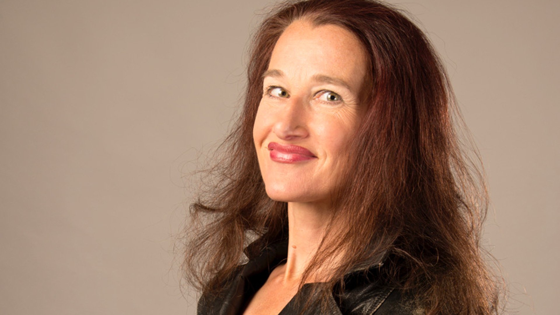 Foto von Maria Maschenka für das Event ‚Prost & Prosa-Improvisation‘, die Künstlerin vor braunem Hintergrund.