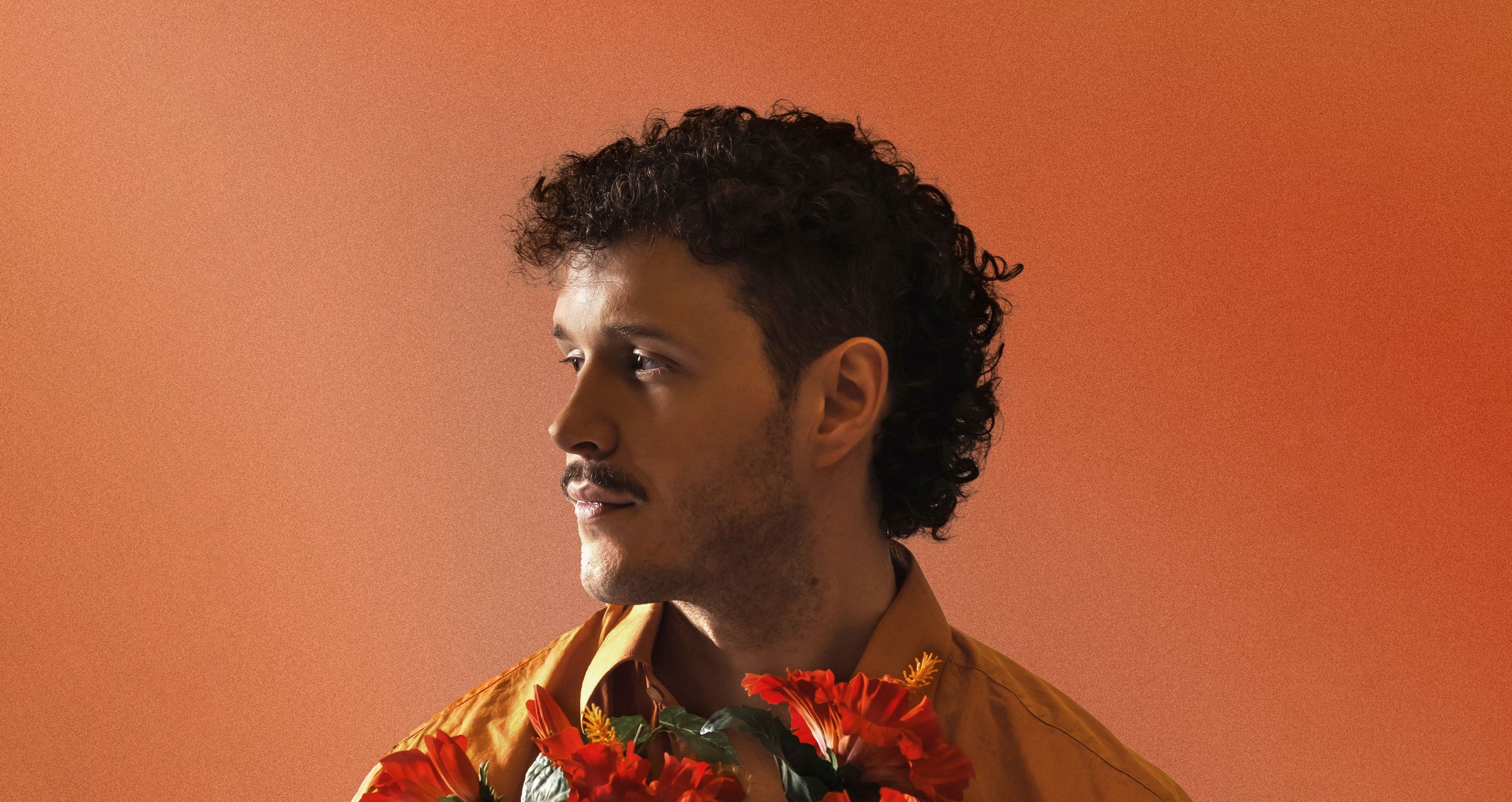Der Künstler Marten vor einem Orangen Hintergrund