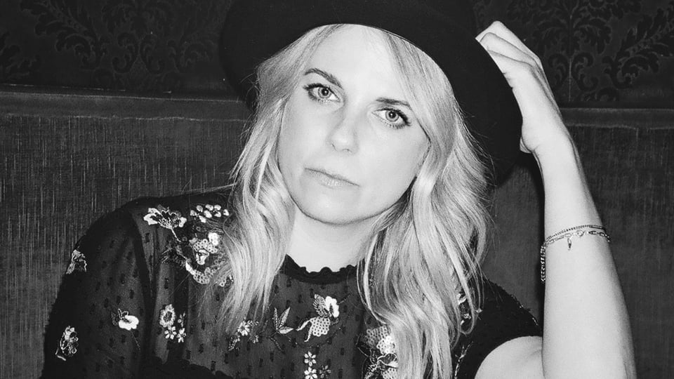 Schwarz-Weiß-Foto für das Event Lisa Schmid: Bittersüß, mit der Künstlerin, die einen Hut trägt.