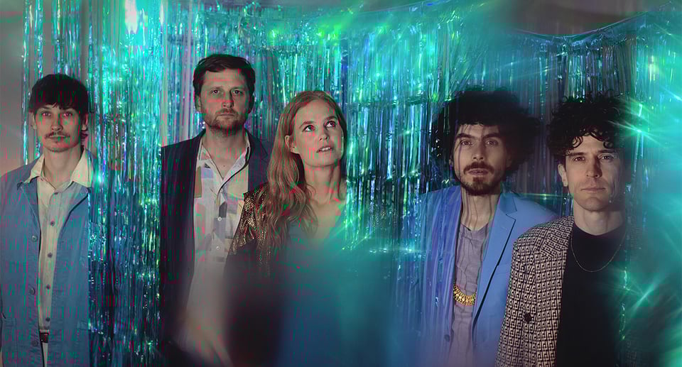 die „Dota“-Band. vier Jungs und ein blondes Mädchen, mit einer Partydekoration in grünen und blauen Farben und Glitzer.