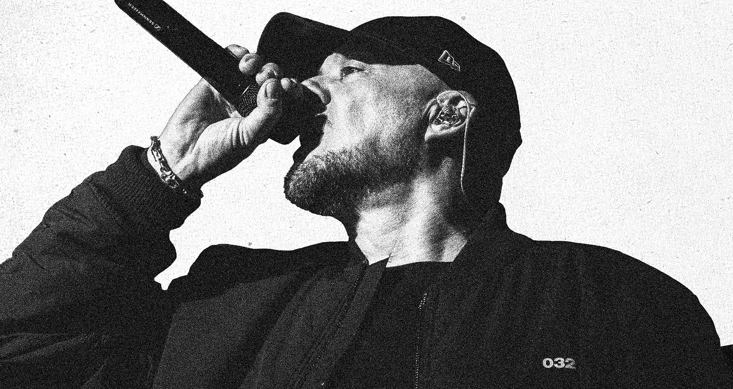 KOOL SAVAS mit Cap singt ins Mikrofon, Schwarz-Weiß‑Foto.