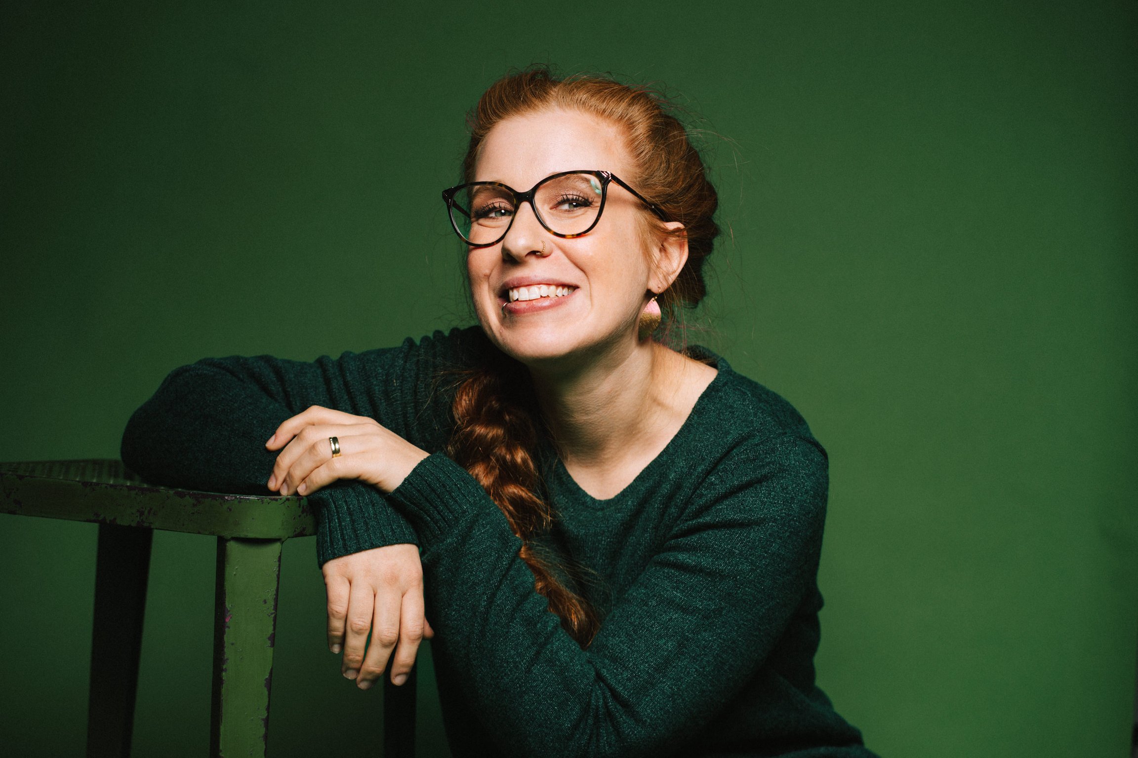 Foto für das Event Sara Brandhuber - A scheena Schmarrn! mit der Künstlerin vor grünem Hintergrund.