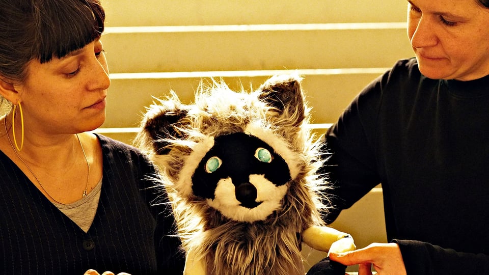 Foto für die Veranstaltung Das Haus vergisst nichts mit zwei Frauen und einer Waschbär-Puppe