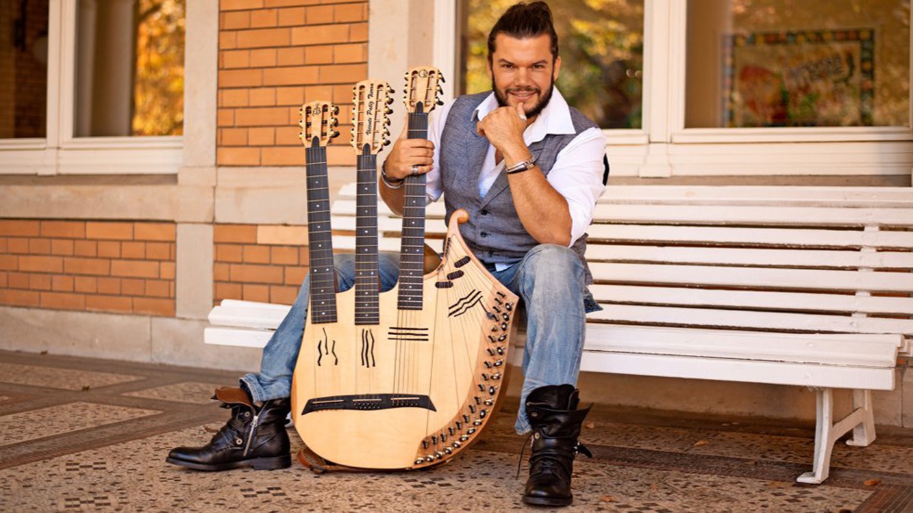 Der Künstler sitzt mit seinem Instrument auf einer weißen Bank