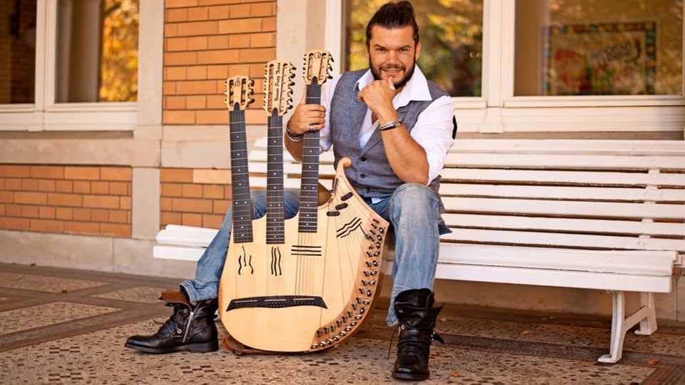 Der Künstler sitzt mit seinem Instrument auf einer weißen Bank