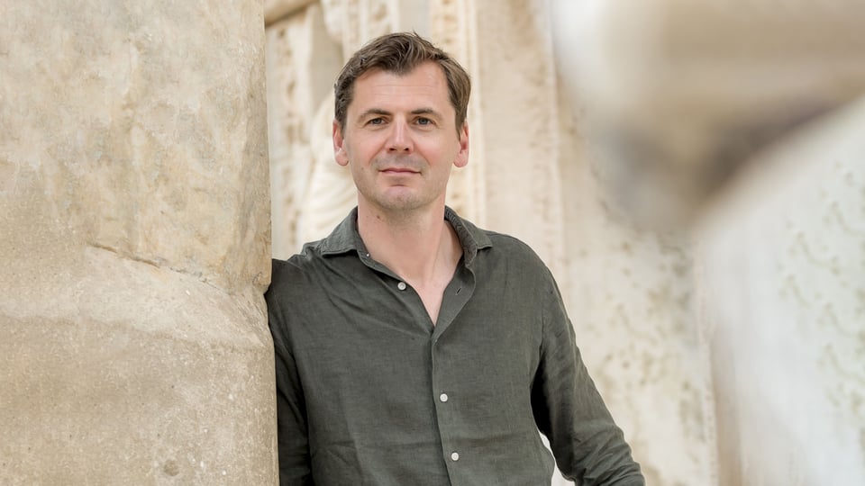 Der Künstler an einer Mauer lehnend