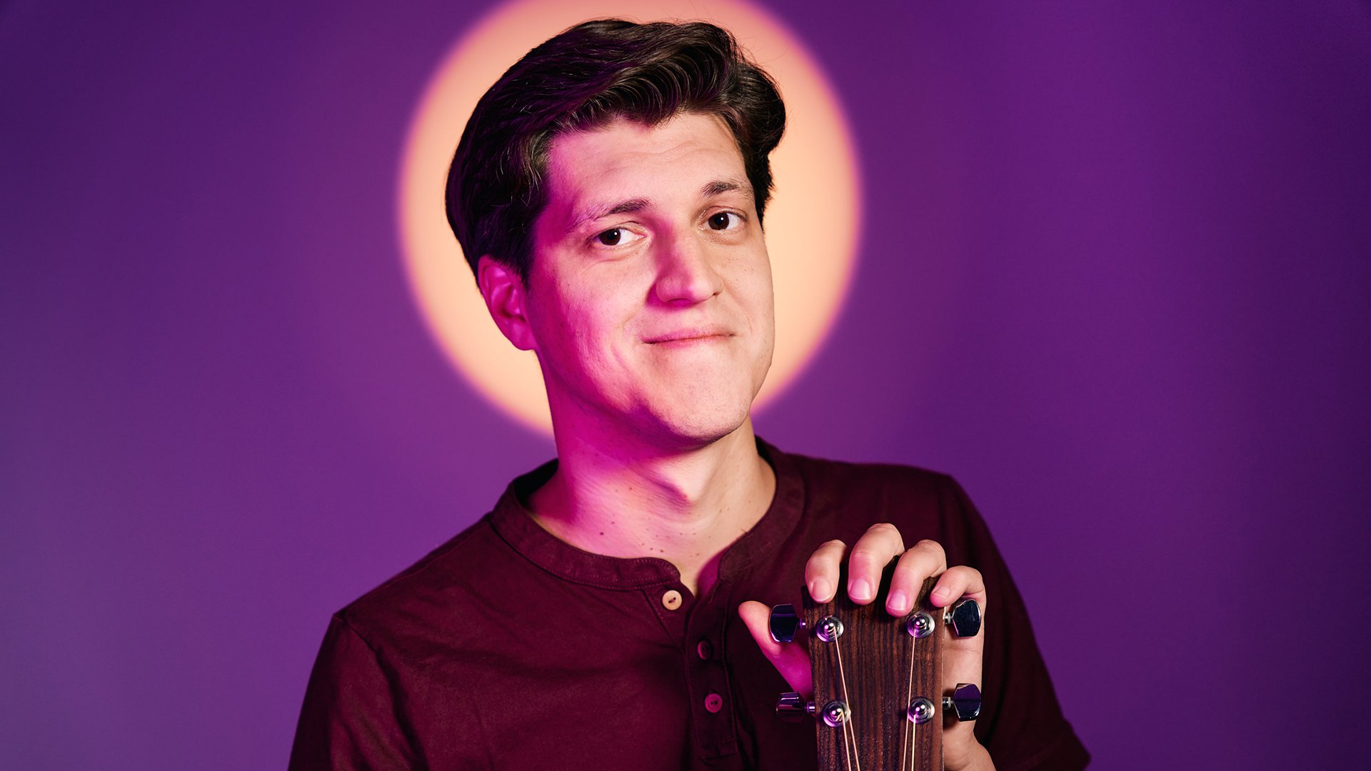 Ein Bild des Künstlers mit Gitarre vor lila Hintergrund