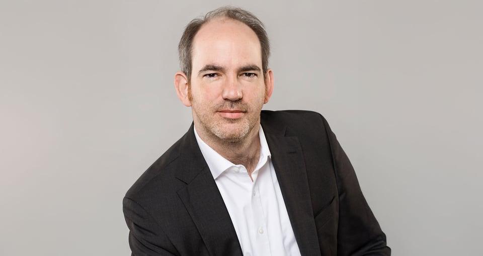Ein Mann im Anzug vor grauem Hintergrund