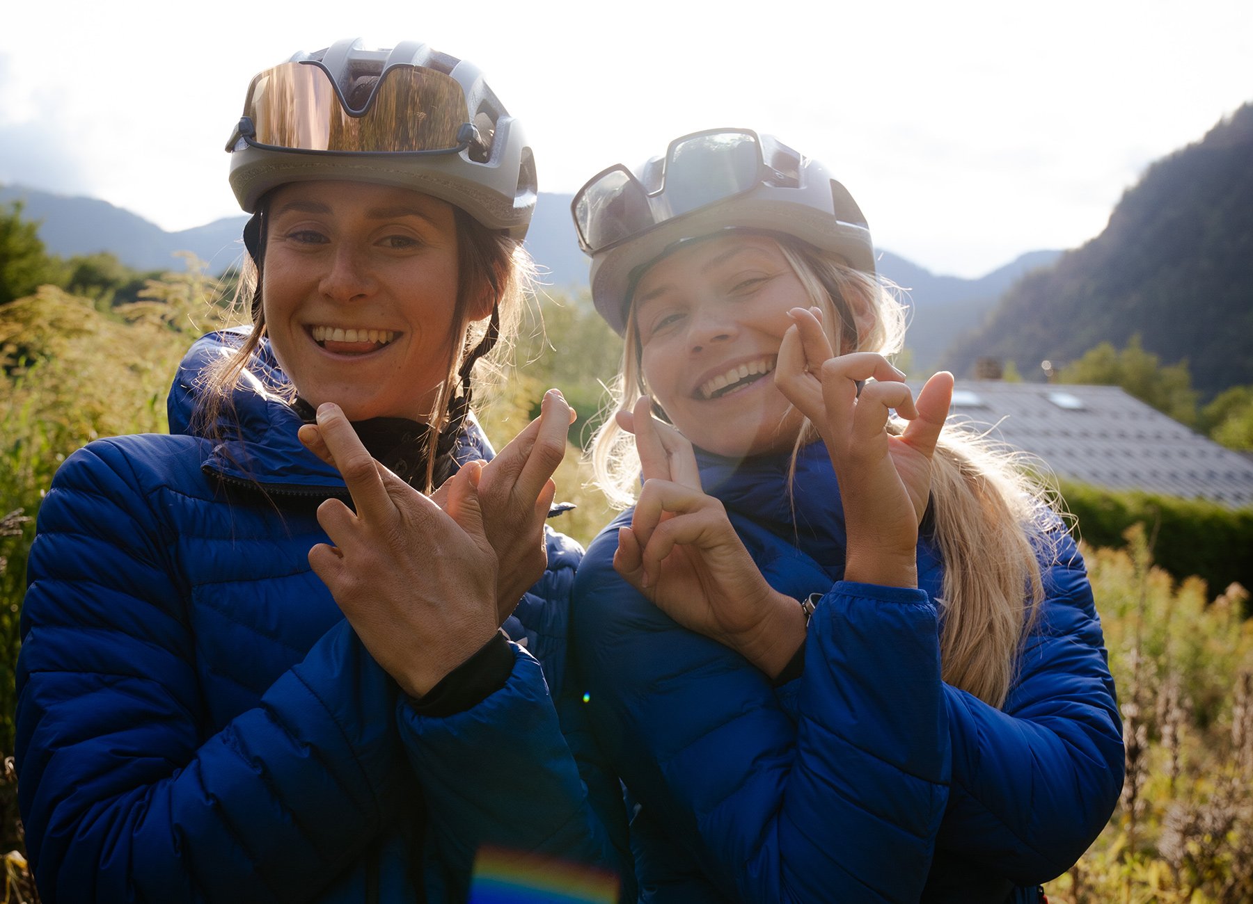 Zwei Damen mit Helm und blauen Anoraks vor Bergkulisse