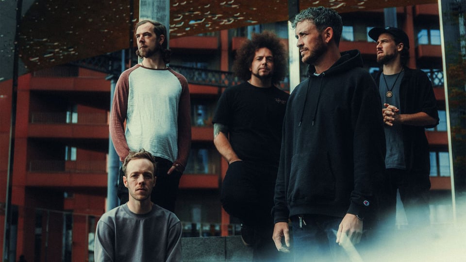 Fünf Personen stehen vor einer Hochhauskulisse