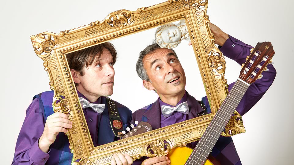 Foto für die Veranstaltung RatzFatz, zwei Personen mit einem goldenen Rahmen.