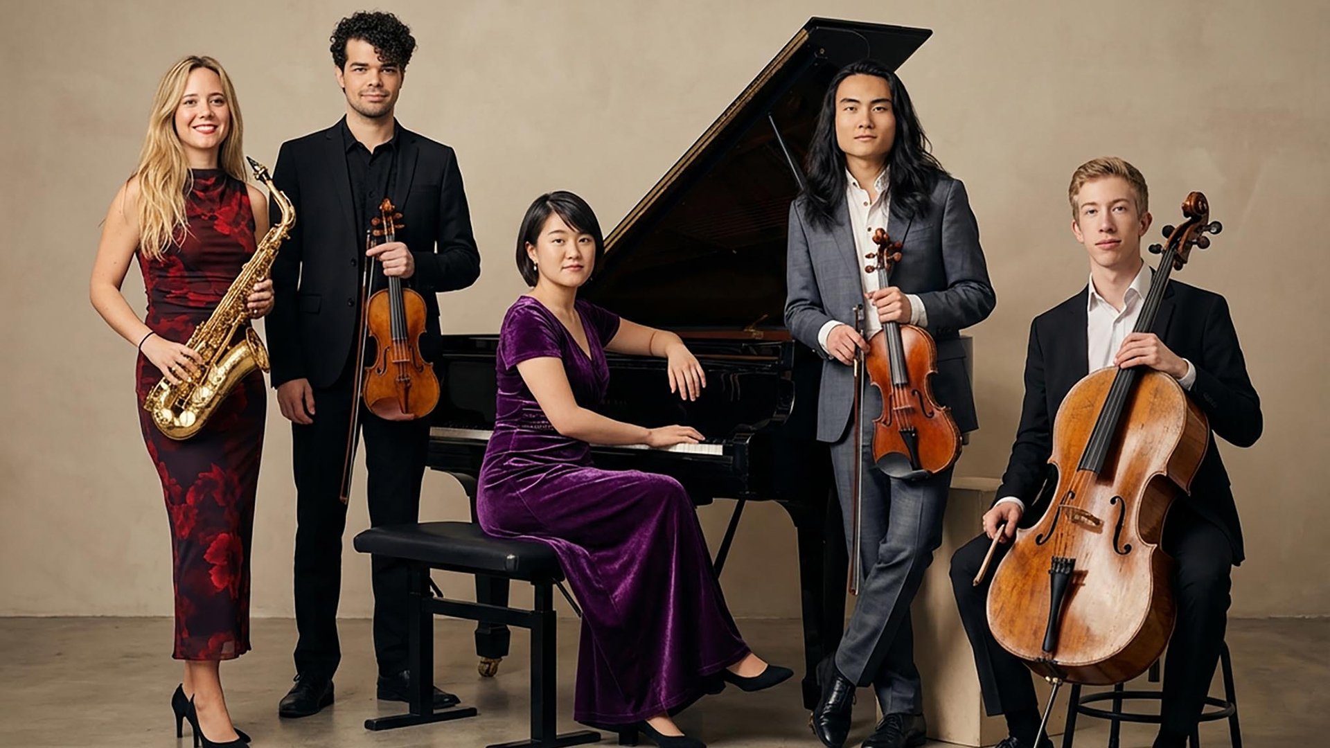 Fünf Musikerinnen und Musiker posieren in eleganter Konzertkleidung vor einem Flügel: eine Saxophonistin, zwei Violinisten, eine Pianistin und ein Cellist. Ensemblefoto zum Konzert mit Werken von Pärt, Klein, Krása, Schulhoff und Schostakowitsch