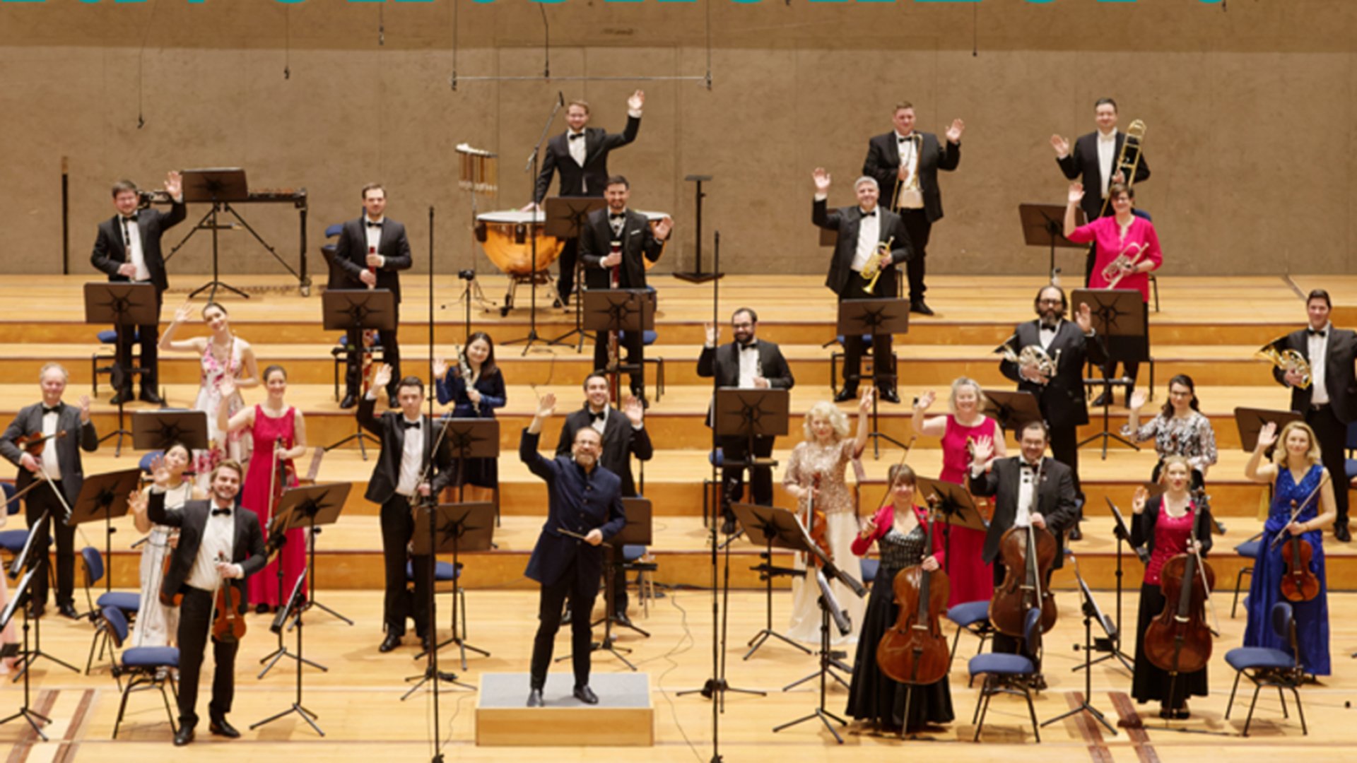 Ein Orchester mit Instrumenten  auf einer breiten Bühne mit Treppen während einer Vorführung 