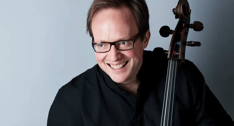 Foto des Künstlers mit einem Instrument vor blauem Hintergrund