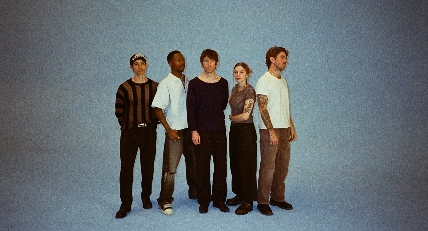 Vier Männer und eine Frau stehend or grau-blauem Hintergrund