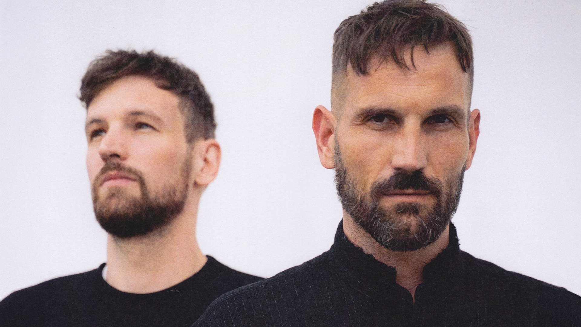 Portrait der beiden Künstler in schwarzer Kleidung mit hellem Hintergrund